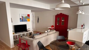 Una sala de estar moderna con un sofá, televisor y mesa de comedor de vidrio.