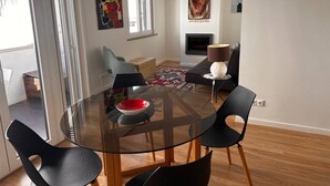 Una sala de estar moderna con una mesa de comedor de vidrio, sillas negras, un sofá y una chimenea.
