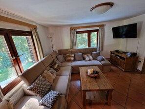 Un salon comprenant un canapé, une table basse, un téléviseur et un meuble en bois.