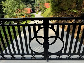 A metal fence with a decorative design, a paved pathway, and greenery in the background.