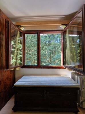 A room with a large window, a wooden bench, and a radiator.