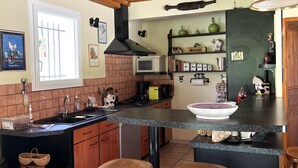 Una cocina con vigas de madera, una isla grande con taburetes, microondas y varios utensilios de cocina.