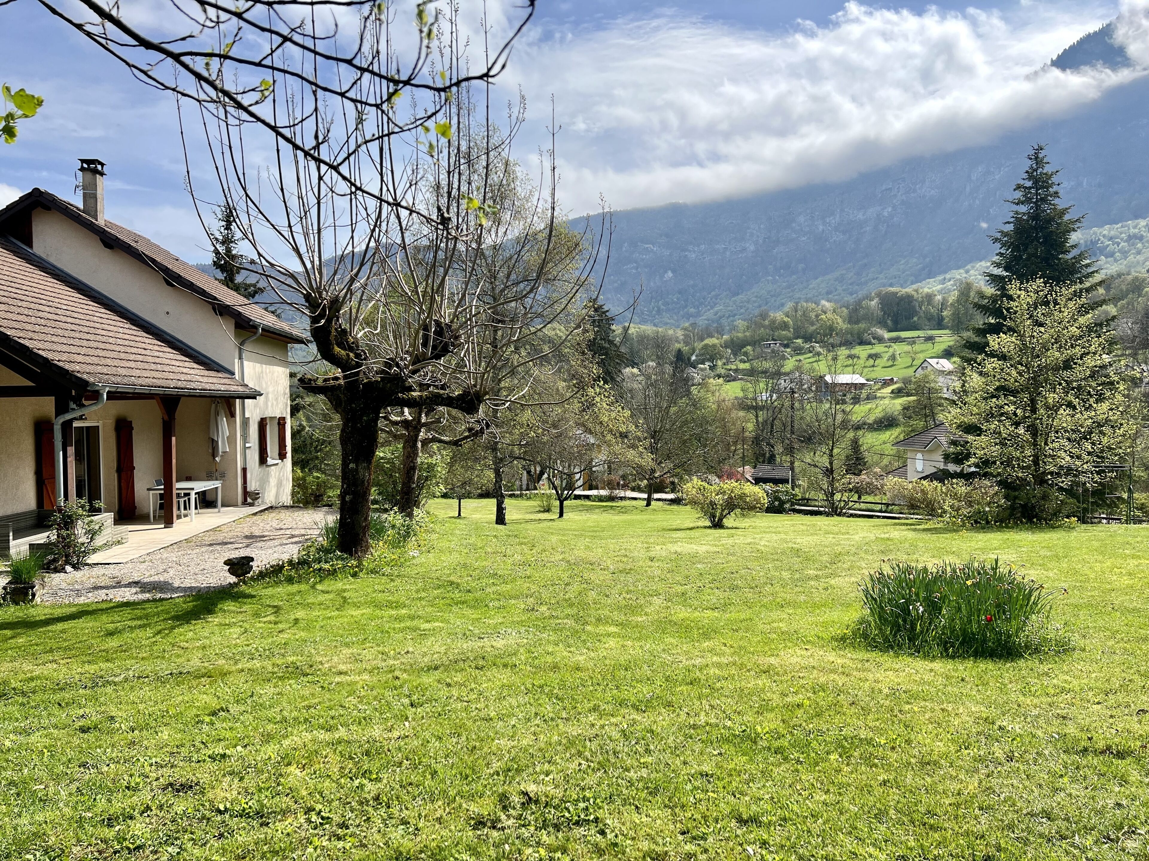 A house with a covered porch, a lawn, and a mountain backdrop.