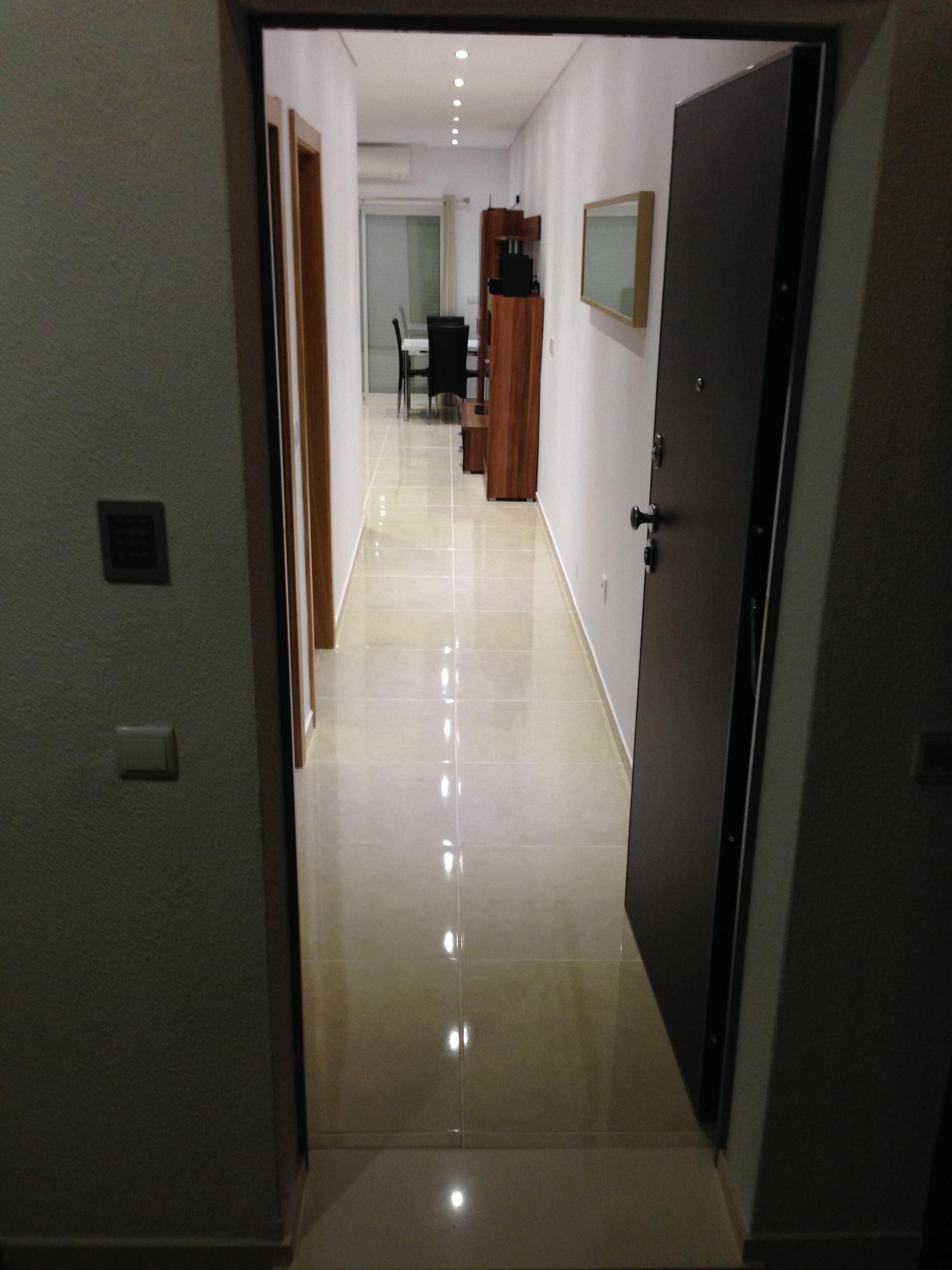 A hallway with a tiled floor leading to a dining area with a table and chairs.