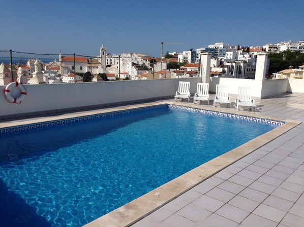 A rectangular swimming pool with clear blue water, surrounded by a tiled deck. - OLD TOWN, Apt. 70m2 on Avenida da Liberdade, AIR CONDITIONING / SWIMMING POOL / FREE Wi-Fi (Albufeira)