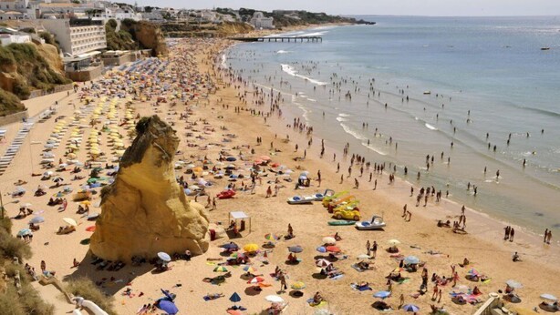 Une plage bondée, avec de nombreux parasols et beaucoup de monde.