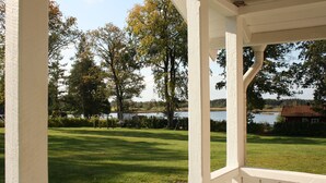 Un espacio al aire libre cubierto con vistas a un lago y una casa al fondo.
