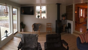 Una sala acogedora con un sofá azul, un sillón de mimbre y una chimenea.