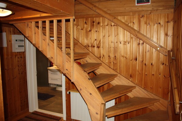 Una escalera de madera con barandilla que lleva a una puerta.