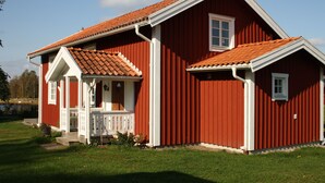 Una casa de madera roja con un porche blanco y una ventana pequeña.