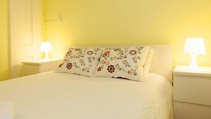 A bed with floral pillows, white bedding, and two bedside lamps. - Apartment Baixa/Chiado view Castle (Lisboa)