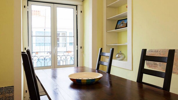 A dining area with a wooden table, chairs, a bowl, and a shelf with decorative items. - Apartment Baixa/Chiado view Castle (Lisboa)
