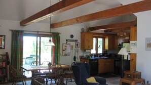 Una sala de estar acogedora con comedor, una cocina con armarios de madera y un amplio ventanal con cortinas.