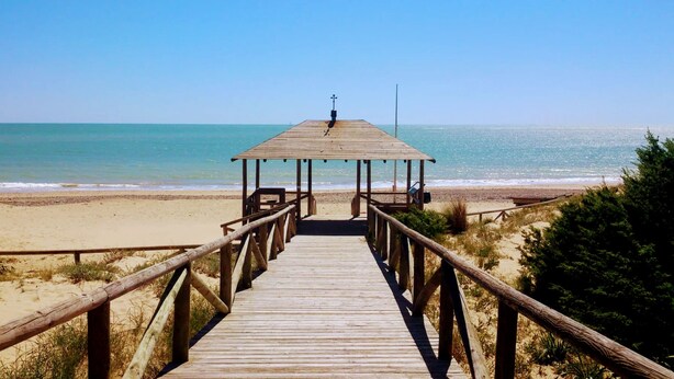 A wooden boardwalk leading to a beach with a wooden shelter at the end. - Excellent apartment in Rota, with pool, Wifi and garage (ROTA)