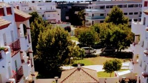 A swimming pool with a small gazebo in the center, surrounded by a well-maintained lawn and adjacent residential buildings. - Excellent apartment in Rota, with pool, Wifi and garage (ROTA)