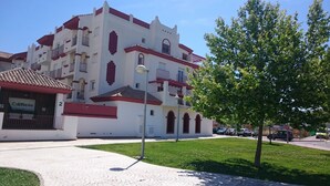 A multi-story building with a white facade and red accents, featuring balconies and a sign that reads "Edificio". - Excellent apartment in Rota, with pool, Wifi and garage (ROTA)