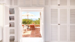 Une chambre avec vue sur une terrasse extérieure, une armoire blanche et un lit.