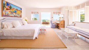 Une chambre avec un grand lit, un bureau, une chaise, un canapé et une vue sur l’extérieur.