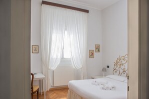 A bedroom with a bed, a desk, and a chair.