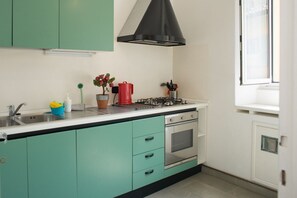 A kitchen with teal cabinets, a gas stove, an oven, and a window.