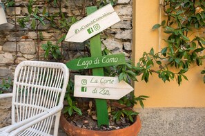 A directional signpost with arrows pointing to different locations, a wicker chair, and a potted plant.