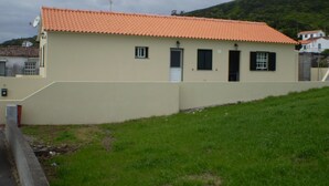 A single-story building with a tiled roof, a small front entrance, and a satellite dish. - Large 2 bedroom apartment (Açores)
