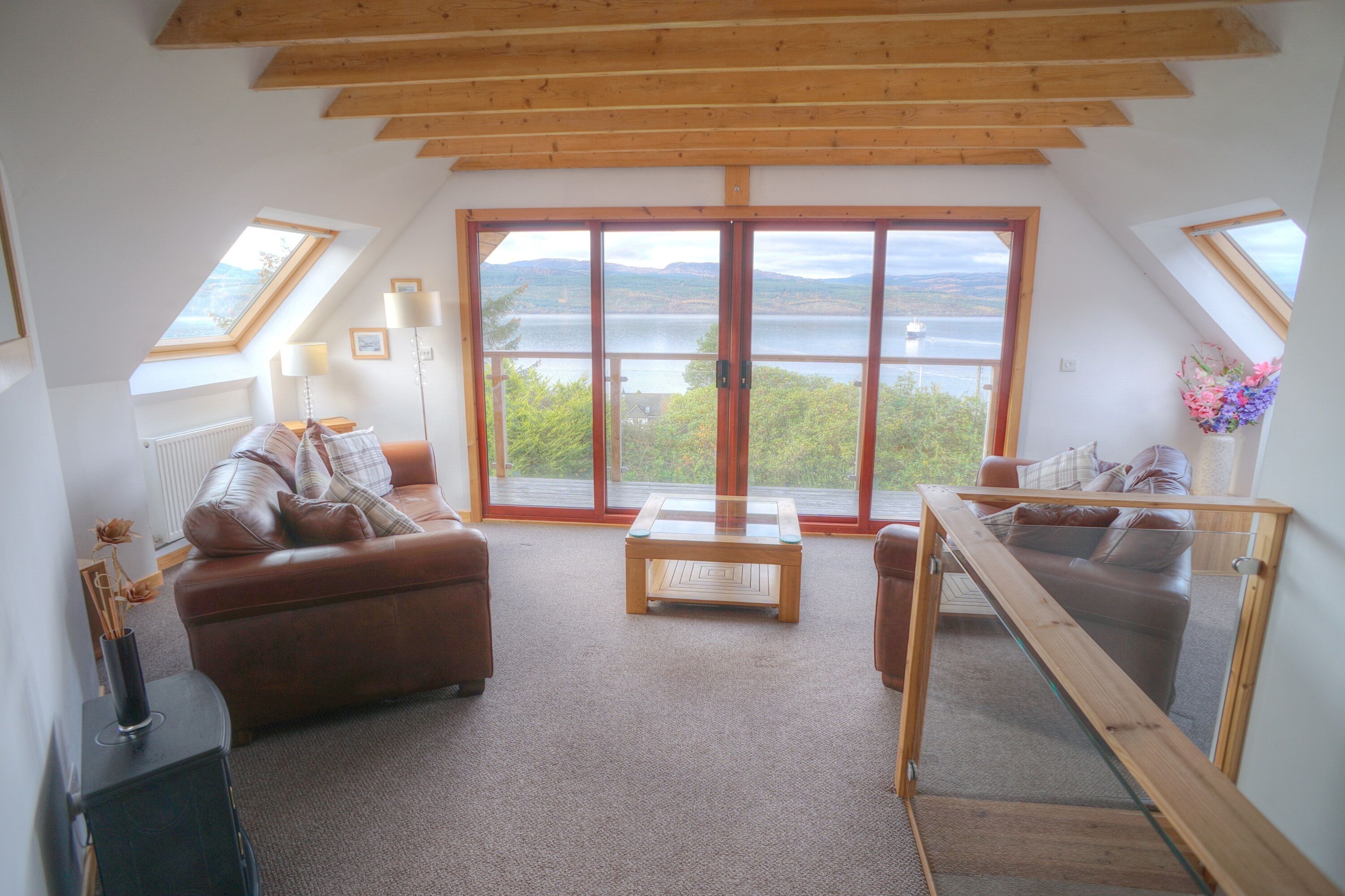 Upper living area with exposed beams. Patio doors to balcony. Glass balustrade.