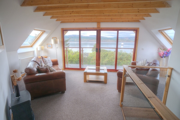 Upper living area with exposed beams. Patio doors to balcony. Glass balustrade.