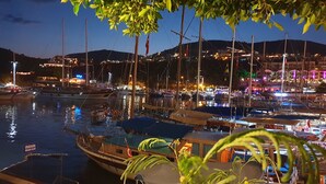 A marina at night with boats docked, a beach club sign, and buildings in the background. - Luxury Villa, Private Pool, Beautiful Gardens, Stunning Sea & Mountain Views (Kalkan)