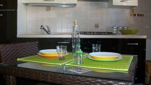 Een keuken met een eettafel voor twee personen, een magnetron en een fornuis.