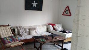 A living room with a sofa, a wooden coffee table, a patterned armchair, and a wall with a star and a circular sign. - Beach apartment in Urb. Private (Algeciras)