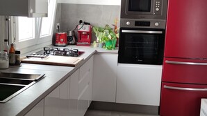 A modern kitchen with white cabinets, a red refrigerator, a built-in oven, and a gas stove. - Beach apartment in Urb. Private (Algeciras)