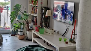 A living room with a white entertainment unit, a green bean bag, a red chair, and a TV on the wall. - Beach apartment in Urb. Private (Algeciras)