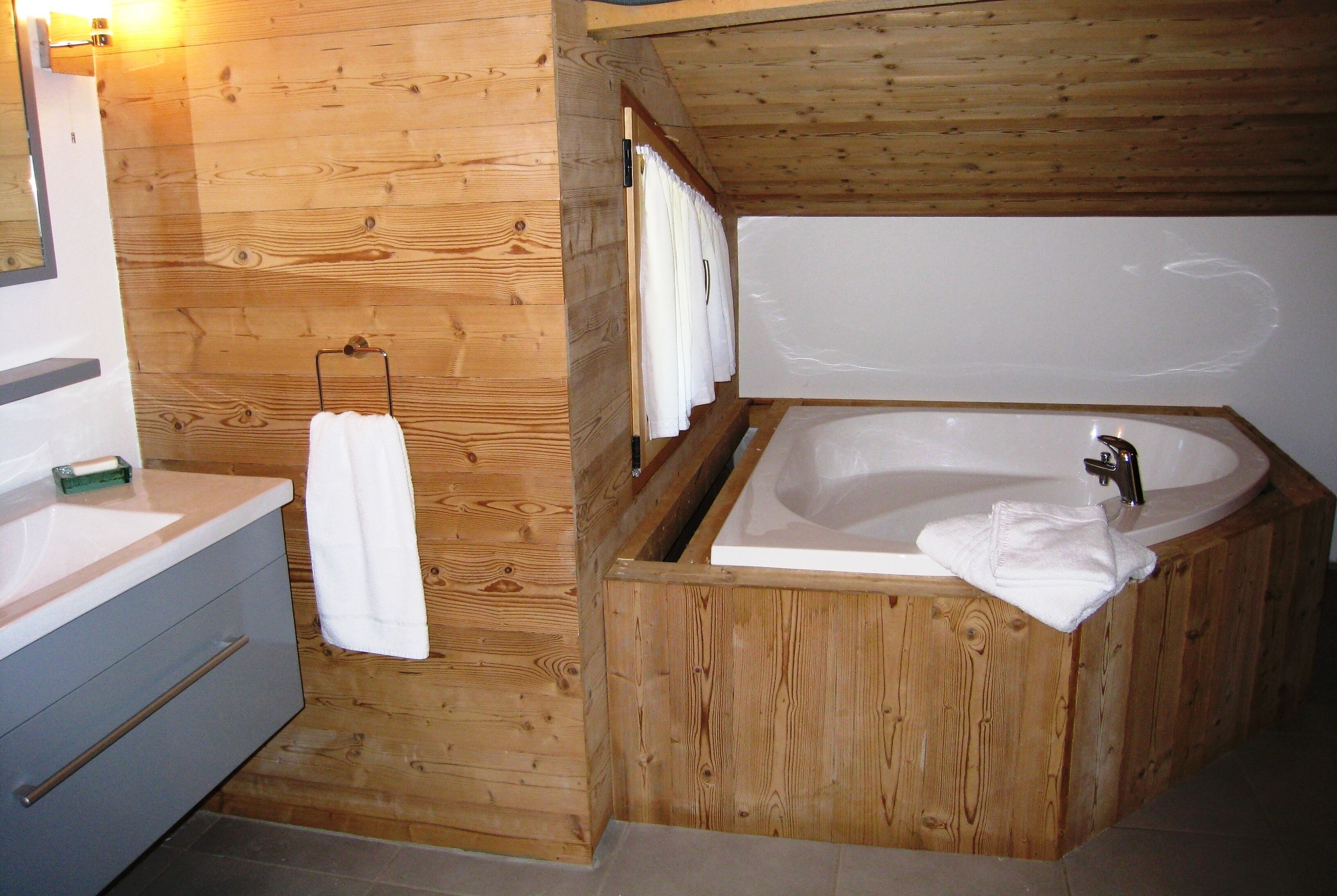A wooden cabin bathroom with a bathtub, a sink, and a towel rack.