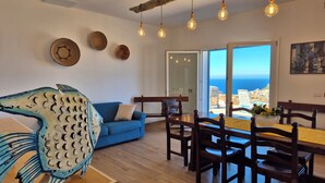 A dining area with a wooden table and chairs, a blue sofa, and a view of the sea through a glass door. - House in the countryside with wonderful views Asinara Gulf and Castelsardo (Castelsardo)