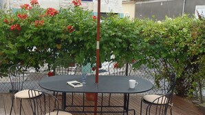 An outdoor patio with a round table and four chairs, surrounded by a wooden deck and a white umbrella. - Fisherman's Cottage with WiFi and views to the harbour. (Mortagne-Sur-Gironde)