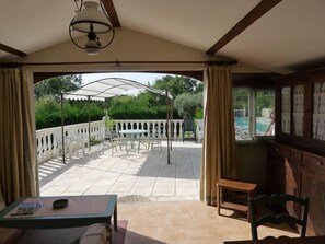 A covered patio with outdoor seating, a pool view, and a wooden interior. - Superb studio with terrace and pool (La Gaude)