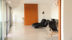 Un'area d'attesa moderna con poltrone in pelle, un pannello decorativo in legno e una porta in vetro che dà sull'esterno.
