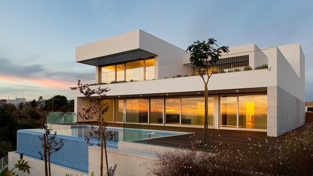 Una moderna casa a due piani con un'ampia facciata in vetro, una piscina sul tetto e un giardino curato.