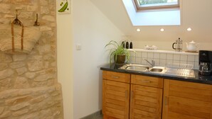 A kitchen with a stone wall, wooden cabinets, a skylight, and a hanging plant. - Beautiful retreat With Panoramic Countryside Views close to Hautefort Chateau. (Hautefort)