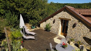 A stone building with a wooden deck, outdoor seating, and potted plants. - Beautiful retreat With Panoramic Countryside Views close to Hautefort Chateau. (Hautefort)
