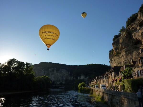 A river with buildings on the right bank and hot air balloons in the sky. - Beautiful retreat With Panoramic Countryside Views close to Hautefort Chateau. (Hautefort)