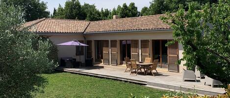 A house with a tiled roof, a patio with outdoor furniture, and a well-maintained lawn.