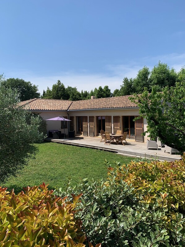 A house with a tiled roof, a patio with outdoor furniture, and a well-maintained lawn.