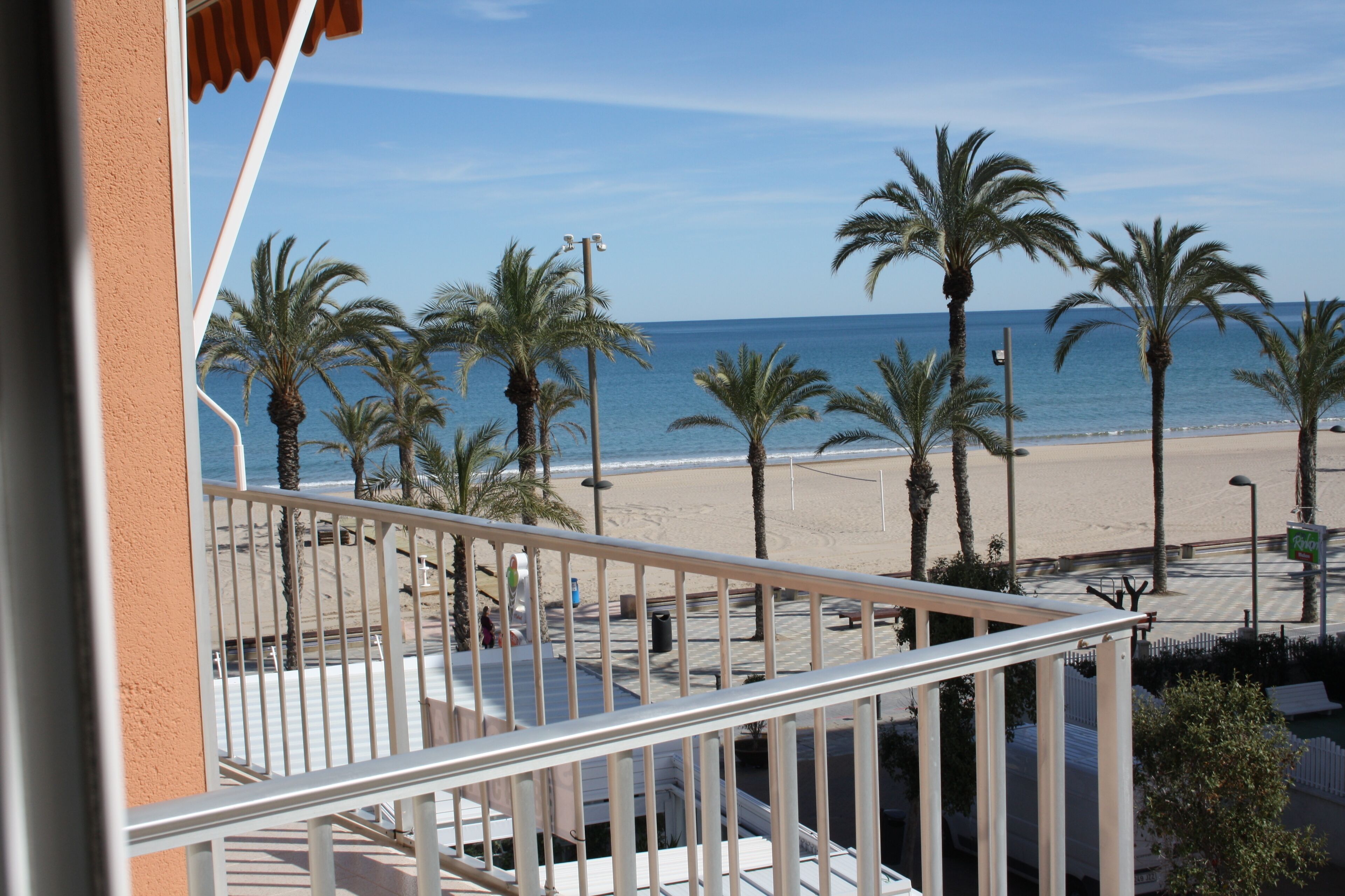Un balcon avec vue sur une plage, des palmiers et l’océan.