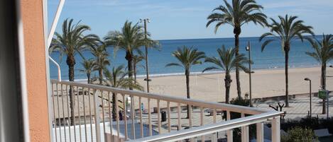 Un balcon avec vue sur une plage, des palmiers et l’océan.