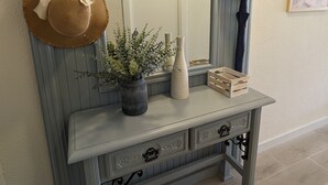 A hallway with a grey wainscoting, a mirror, a console table with decorative vases, a potted plant, and two hats hanging on hooks. -  TORREMAR APARTMENT IN FRONT OF THE SEA.  VT- 450557-A (ALICANTE/ALACANT)