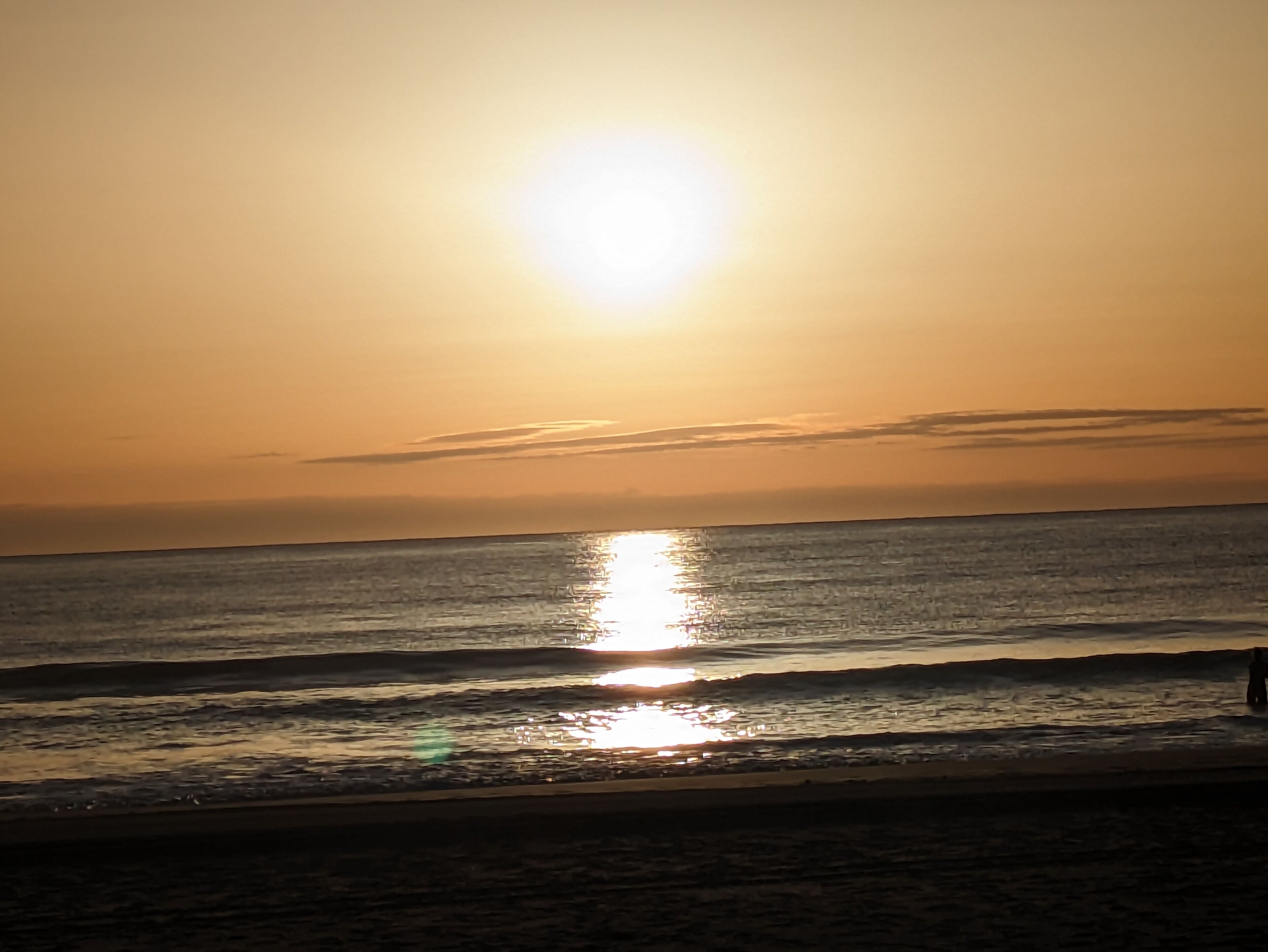 A sunset over a calm sea with a clear horizon.