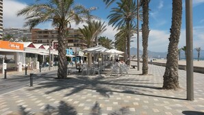 A coastal promenade with outdoor seating, palm trees, and a view of the beach and mountains. -  TORREMAR APARTMENT IN FRONT OF THE SEA.  VT- 450557-A (ALICANTE/ALACANT)