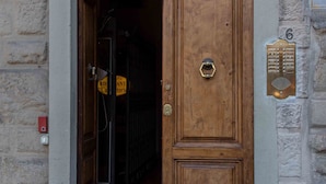 A wooden door with a brass knocker, a metal intercom, and a numbered plaque on the wall. - Magic Signoria Apartment  (Firenze)